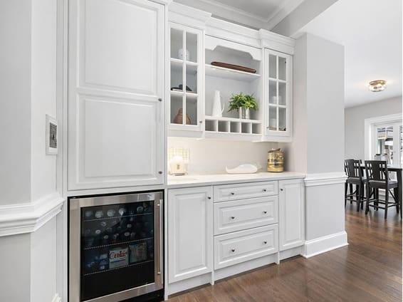Built-in white cabinetry with wine fridge after cabinetry refinishing
