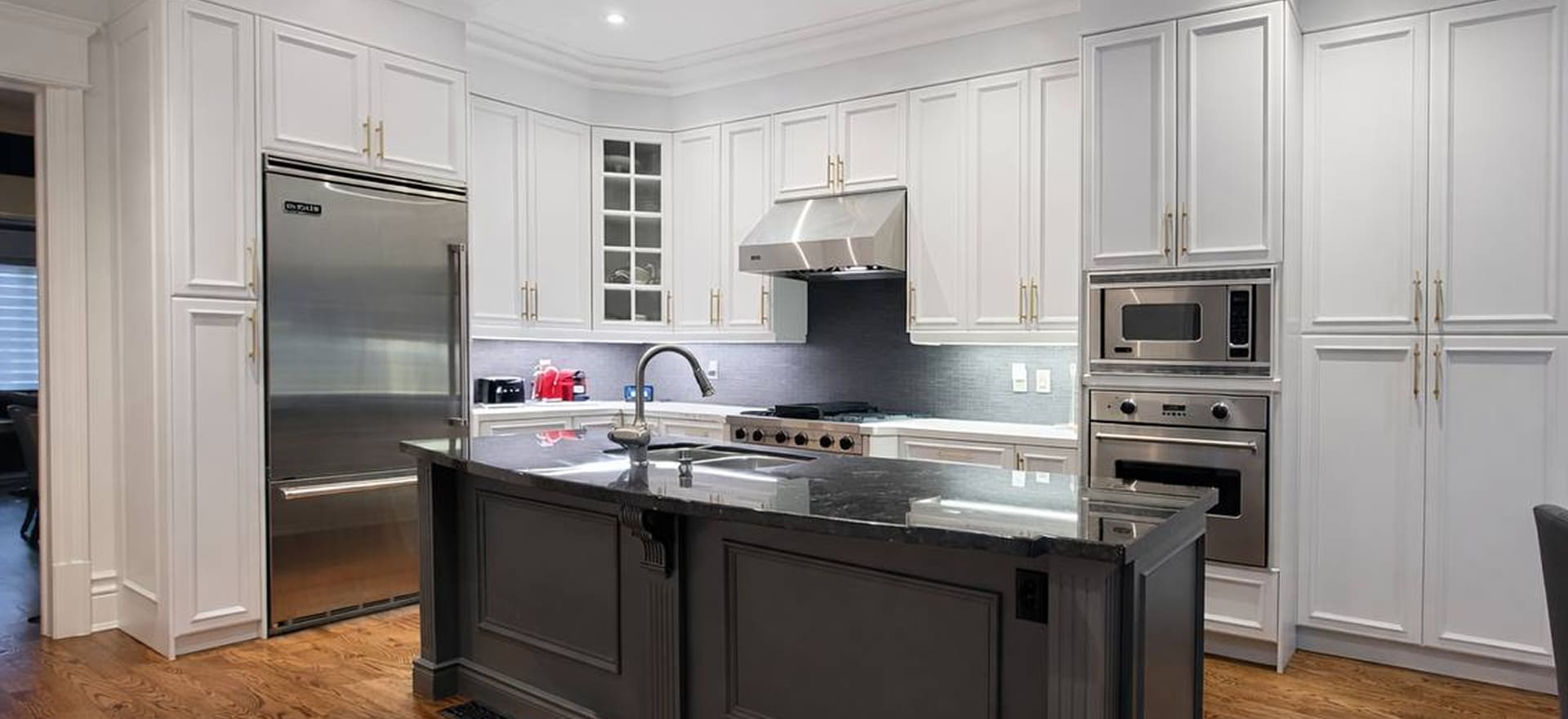 White kitchen with black granite island representing Rad Dezign cabinet refacing services
