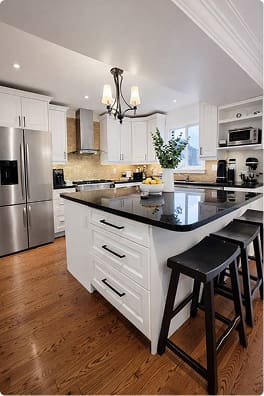White kitchen cabinets with black island and bar stools after cabinet refacing